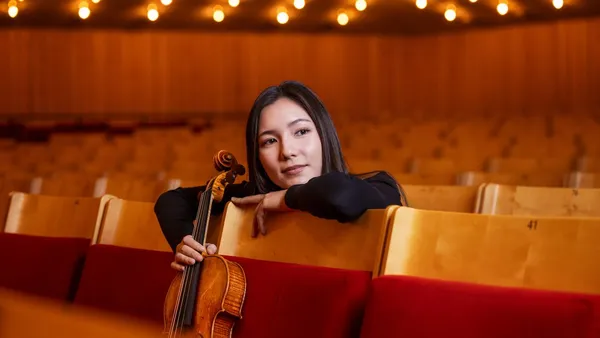 Ami-Louise Johnsson sitter på parkett i Berwaldhallen och håller i sin viola .