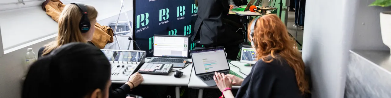 Tre kvinnor sitter och jobbar id mixerbord och med dator med P3-loggor på skärm framför. 