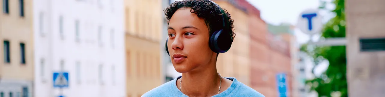 Ung kille med hörlurar i stadsmiljö. 