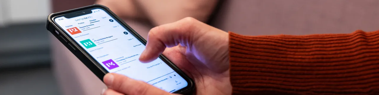 Någon har en mobil i handen med Sveriges radios app.