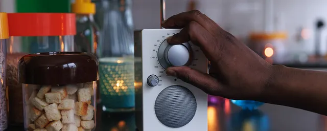 köksmiljö. FM-radio. Hand syns som skruvar på en FM-radio för att få n rätt frekvens.. 