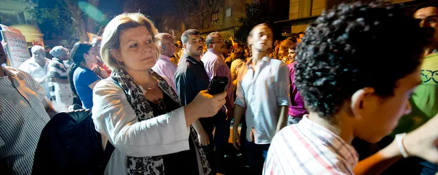 Reportern  Cecilia Uddén tar upp ljud med mobilen i folkmassa.